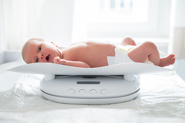 image depicting baby being weighed